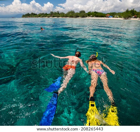 Two ladies snorkeling in tropical sea at sunny day
