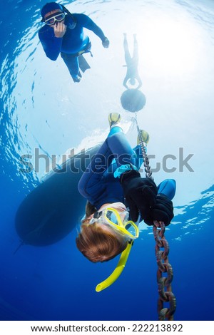 Lady free diver descending along the metal chain using his hands (free immersion). Safety buddy descending close to athlete