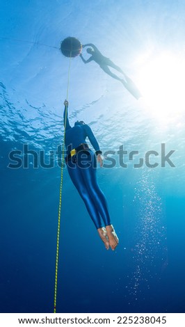 Lady free diver ascending along the rope linked to the buoy on surface. Free immersion discipline