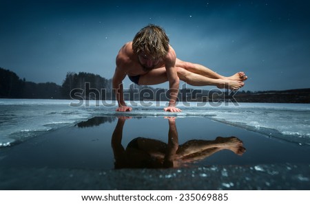 Man doing yoga exercise (parsva bakasana) on the ice of frozen lake