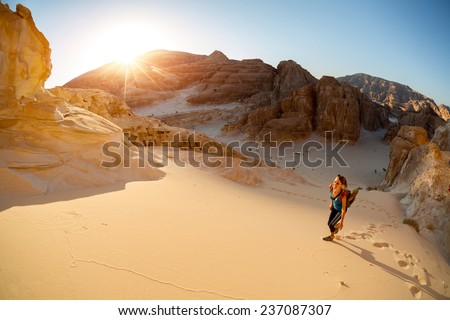 Hiker walking on sand in the desert with valley on the background