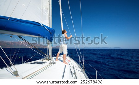 Young man standing on the yacht in the sea at sunny day