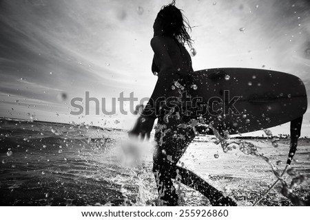 Lady surfer running into sea with surf board