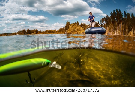 Split shot of the fisherman with rod in the boat and underwater view of the bright wobbler bait with hook