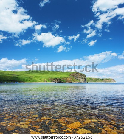 Blue sea with rocks land and blue sky with clouds