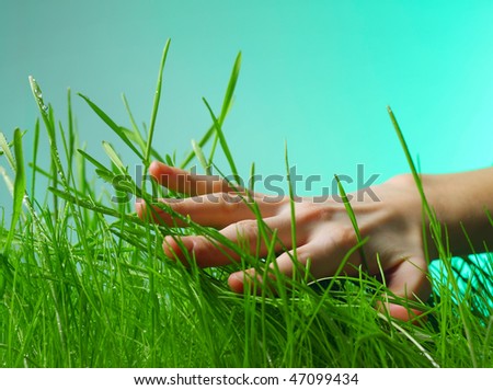 Hand above green wet grass on green background