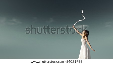 Young woman in white dress with white ribbon over dark sky background