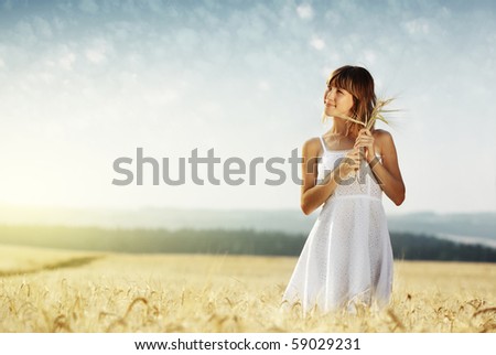 Young smiling woman in white dress standing in field