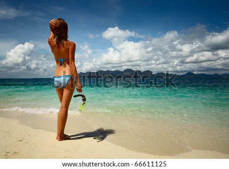 Young woman with wet skin holding a mask and going to snorkeling in clear sea