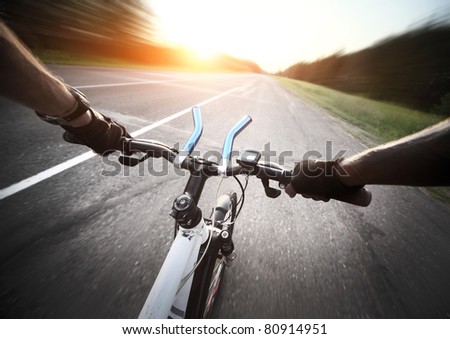 Rider's hands in gloves on a bicycle handlebar. Motion blurred