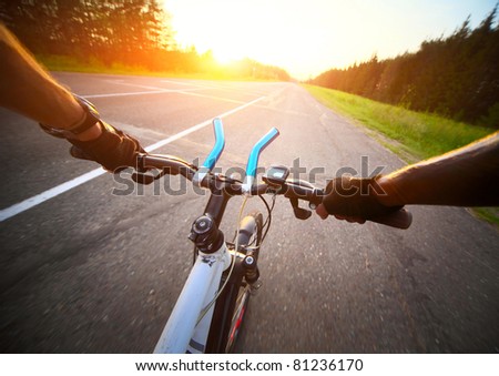 Rider\'s hands in gloves on a bicycle handlebar. Motion blurred asphalt road