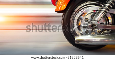 Part of a luxury motorcycle with blurry asphalt road