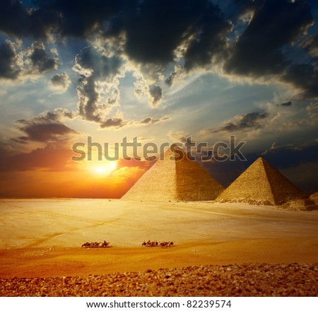 Grate pyramids in Giza valley in Egypt with group of bedouins on camels riding through desert