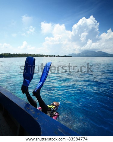 Diver doing back flip into blue transparent sea from a boat\'s board