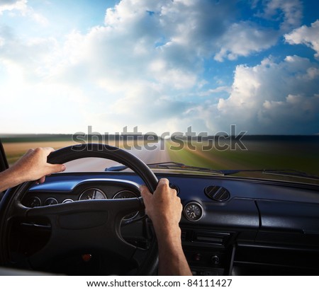 Driver\'s hands on a steering wheel and motion blurred road