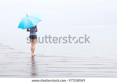 Woman with umbrella standing on a wet wooden floor