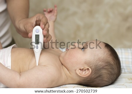 mother measures the temperature of a smiling child