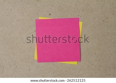 yellow and pink sticky note on brown wall
