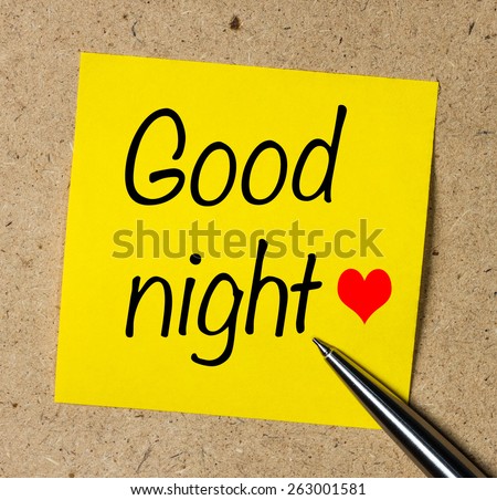 Note with Good night and red heart on the brown wall with pen