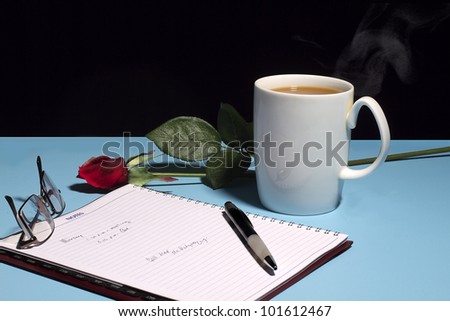 Work desk with red rose and cup of coffee