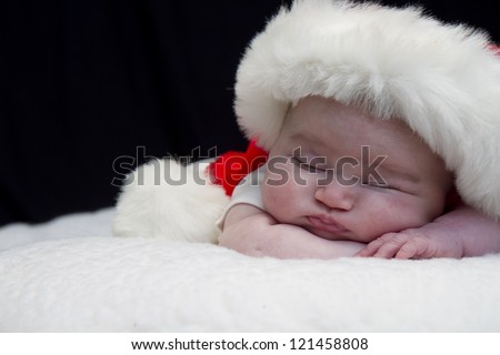Baby girl wearing red santa hat while sleeping and peeking at times