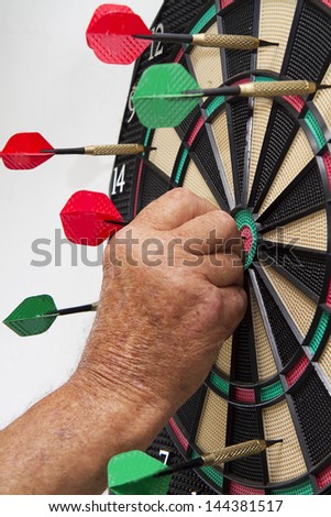 Man pulling darts of dart board