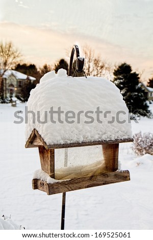 Bird feeder early morning with pile of snow sitting on top of it