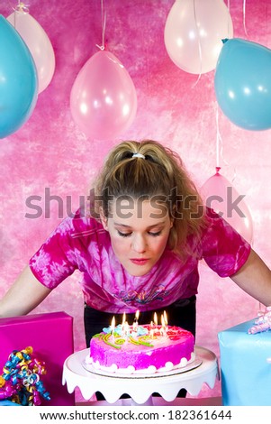 Girl\'s birthday party celebration with cake and balloons with girl blowing out candles