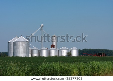 Large silver storage bins on a farm waiting to store various cut crops.