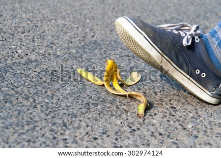 man\'s foot above banana peel laid on road
