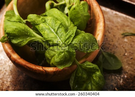 A bunch of fresh basil leaves on a vintage metal tray inside of olive tree bowl