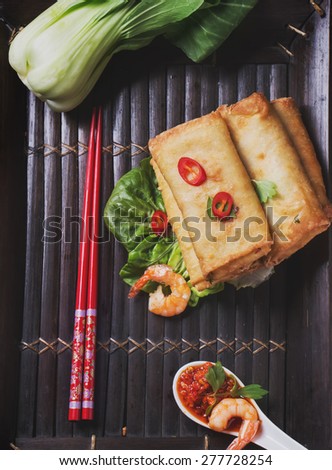 Fried spring rolls with  shrimps, bok choi, chili pepper, hot sauce on a vintage bamboo tray