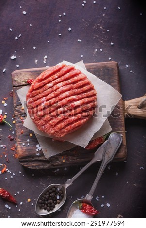 Raw Ground beef meat Burger steak cutlets with seasoning on vintage wooden boards, black background