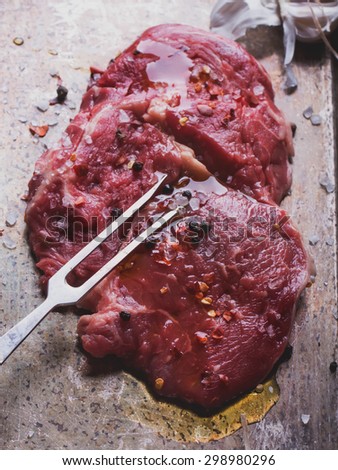Raw fresh meat Ribeye Steak, with seasoning and meat fork on vintage metal tray