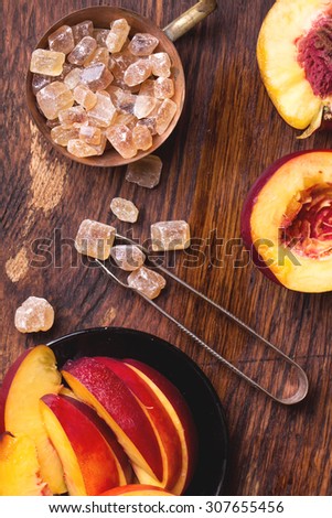 Refreshing iced green tea with peaches and mint, served in a glass with ice cubes and brown sugar on rustic wooden board, selective focus