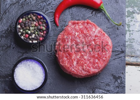 Raw meat ground burger on the black slate board ready to be cooked