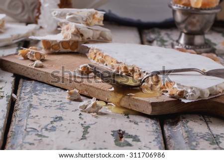 Traditional Spanish Christmas candy turron served on rustic wooden board with honey, almonds and sugar candies on rustic background
