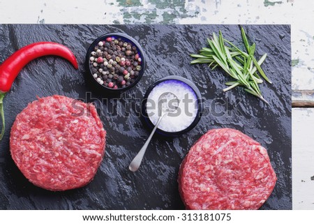 Raw meat ground burger on the black slate board ready to be cooked