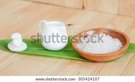 Sea salt in the wood plate on the leaf with stone and a jar of mineral water