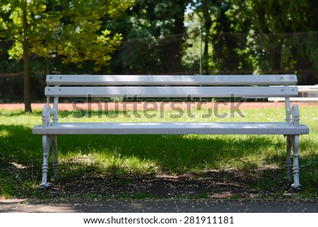 Park bench near tennis court. White iron bench, still in usable condition. Photographed in park Palic, Serbia
