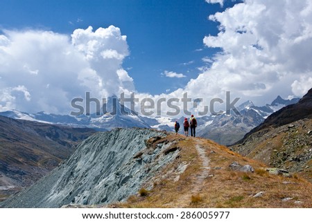 group of friends in hiking in high mountains. snow-capped peaks, glaciers and Fantastic sky background with blue clouds