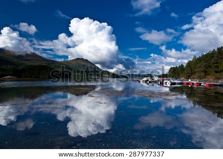 Norway fjord boat station. Beautiful sky with clouds reflected in clear water