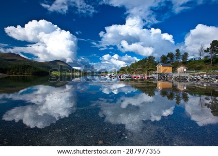 Norway fjord boat station. Beautiful sky with clouds reflected in clear water