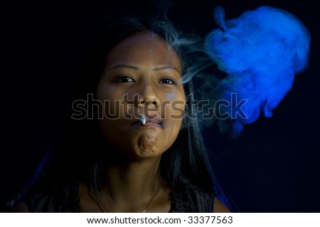 thai-indian woman smoking in dark room with blue back light.