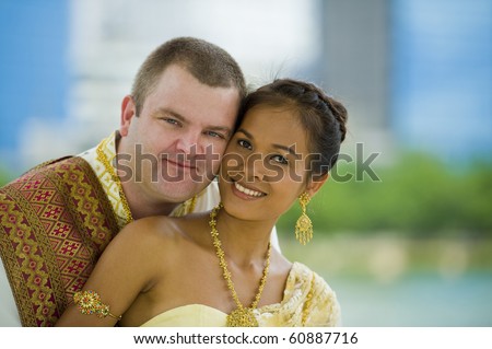 happily married couple in traditional thai wedding clothes posing in a park