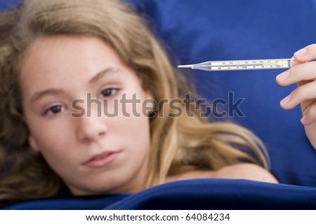 girl sick in bed, having over 39?C /102?F fever. with a shallow depth of field - focus on thermometer.