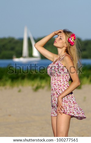 The girl who dreams of traveling. Yong woman standing on a beach with sailing ship