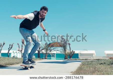 Skateboarder doing a skateboard trick. fashionable boy goes in and skate on the blue sky background. skateboarder takes a walk in a garden .