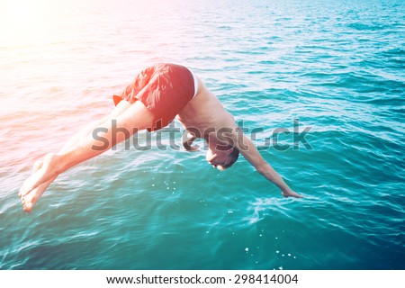 boy across from his boat on a hot summer day. a man with a refreshing bath in the ocean blue from his yacht. boy in costume plunges into the sea.