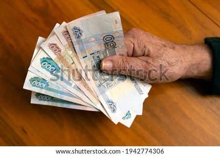 Elderly man holding russian ruble banknotes in hand. The concept of pension, payment and money savings.